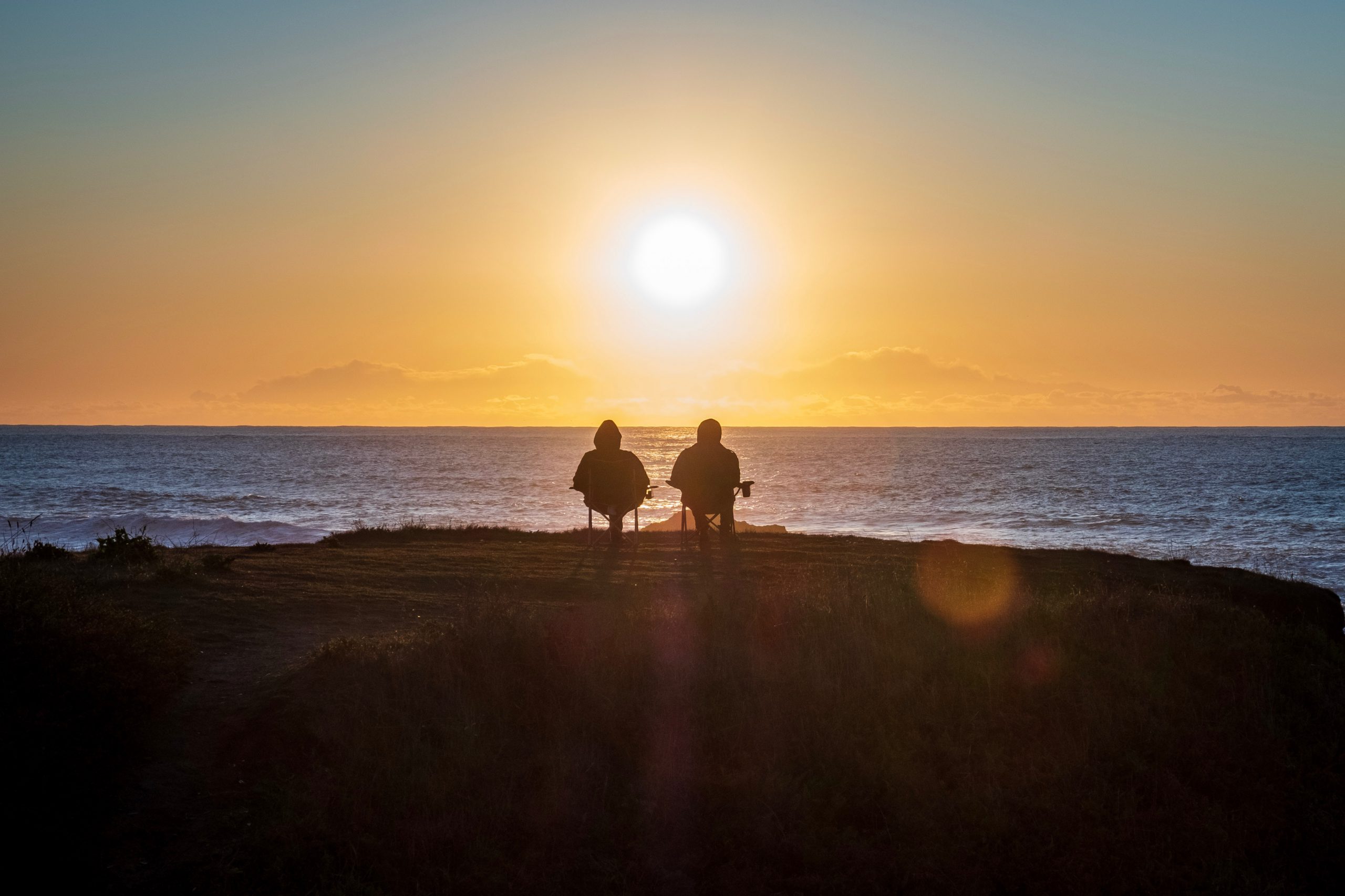 gepensioneerden die naar een zonsondergang boven zee kijken