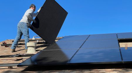 Foto van een persoon die een zonnepaneel installeert op een dak bij een artikel over ongevallen die gebeuren tijdens het installeren van zonnepanelen op een dak