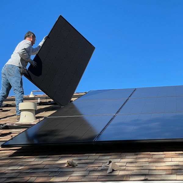 Foto van een persoon die een zonnepaneel installeert op een dak bij een artikel over ongevallen die gebeuren tijdens het installeren van zonnepanelen op een dak