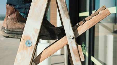 Een foto van een persoon die op een ladder staat bij een blog over werkgeversaansprakelijkheid en huis-tuin-en-keukenongevallen, zoals het vallen van een ladder