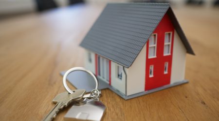 Een foto van een miniatuurmodel van een huis met daarnaast een sleutel van een huis bij een blog over een uitspraak van de rechtbank over de aansprakelijkheid van een woningmakelaar.