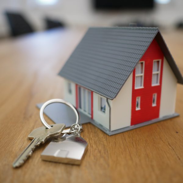 Een foto van een miniatuurmodel van een huis met daarnaast een sleutel van een huis bij een blog over een uitspraak van de rechtbank over de aansprakelijkheid van een woningmakelaar.
