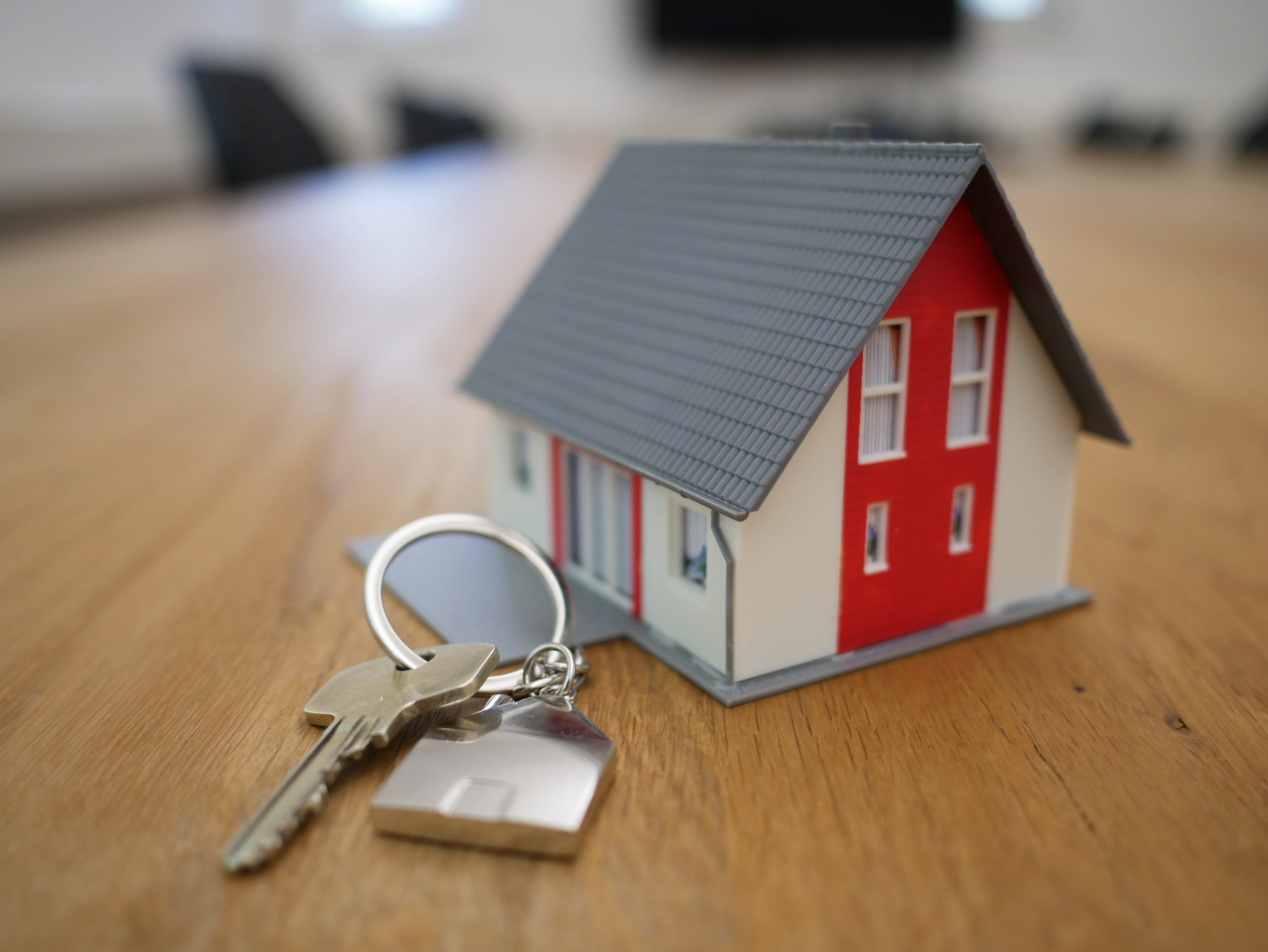 Een foto van een miniatuurmodel van een huis met daarnaast een sleutel van een huis bij een blog over een uitspraak van de rechtbank over de aansprakelijkheid van een woningmakelaar.