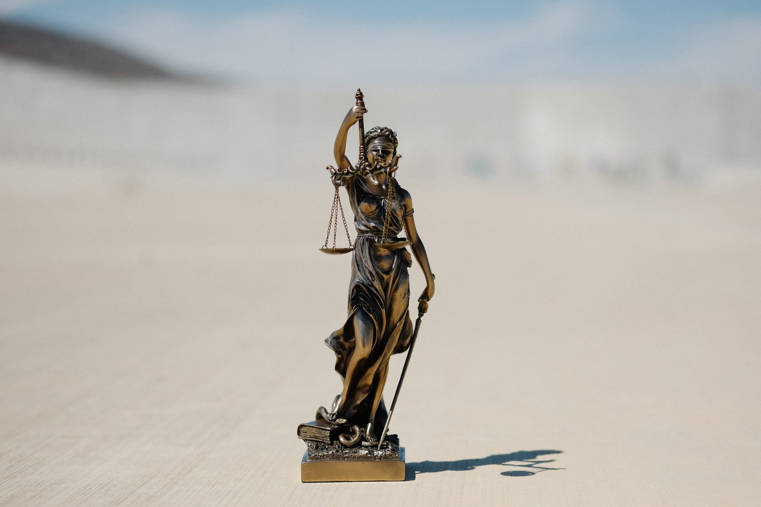 Een foto van een beeldje van Vrouwe Justitia bij een juridisch artikel.